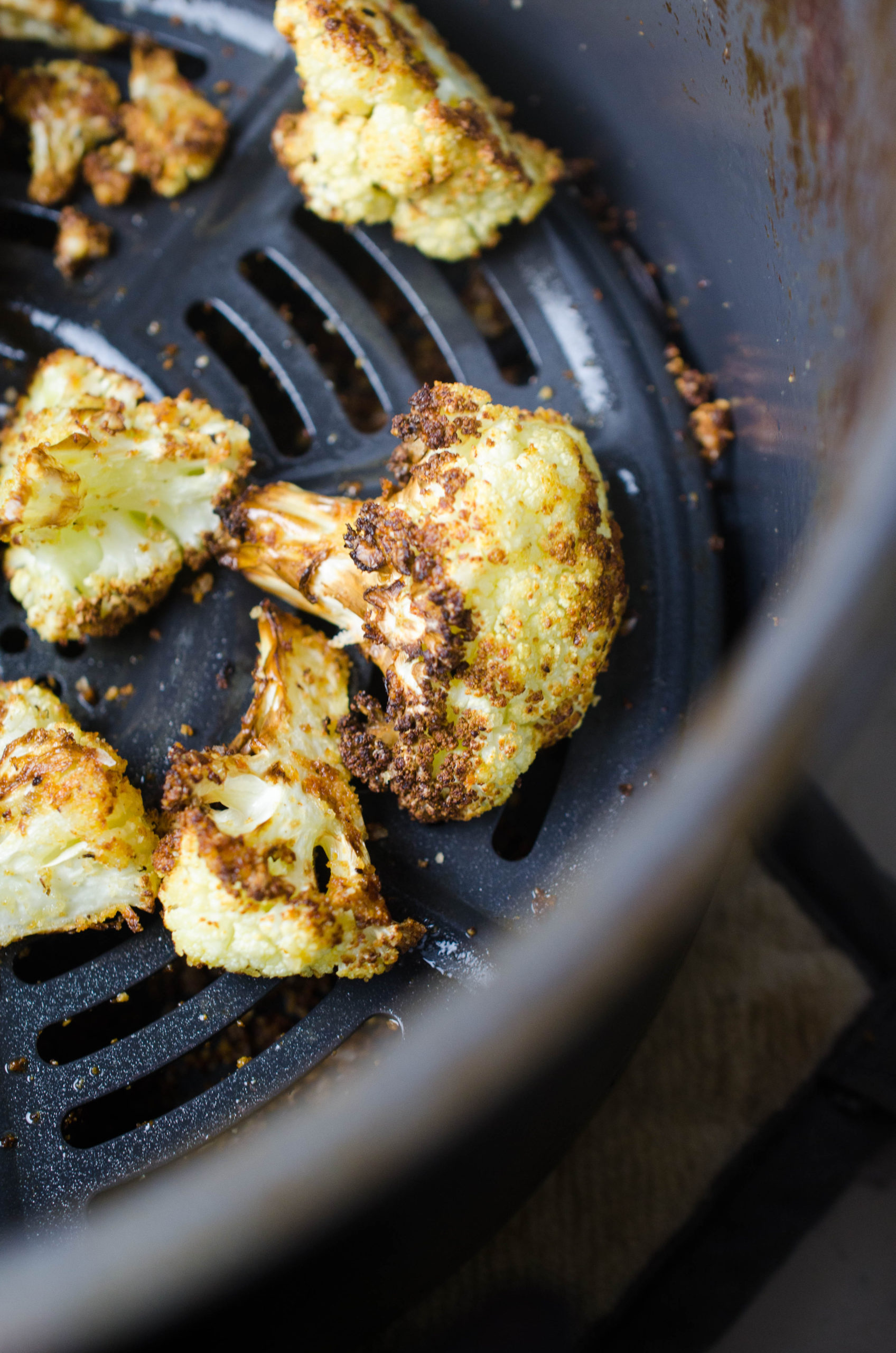 Single layer of cauliflower in air fryer basket.