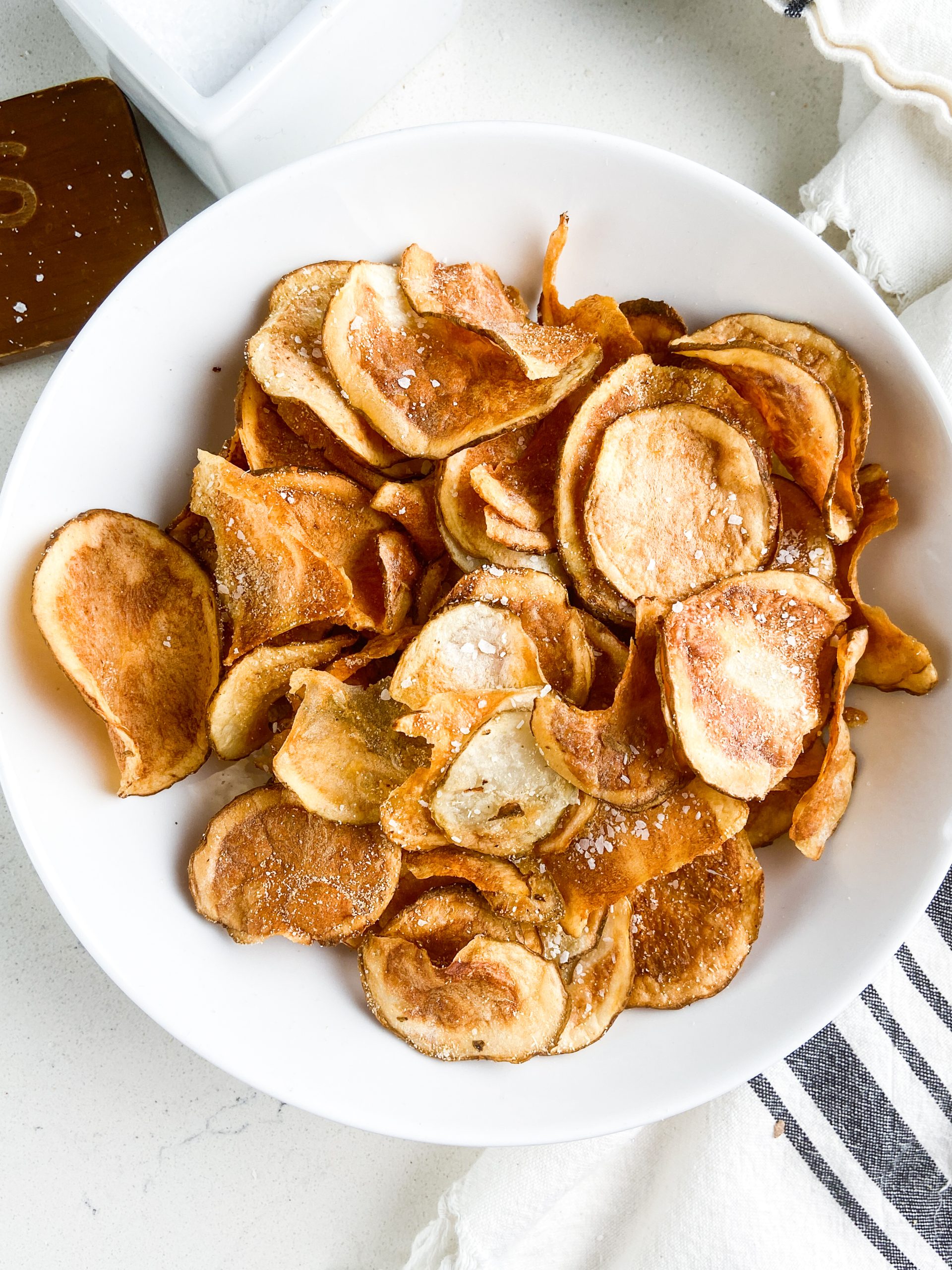 Overhead photo of air fryer potato chips in a white bowl.