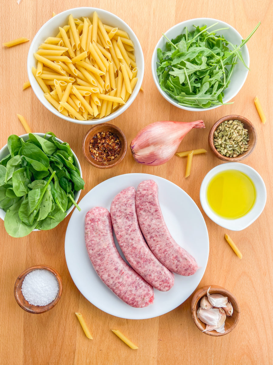 Overhead photo of ingredients needed for sausage arugula pasta.
